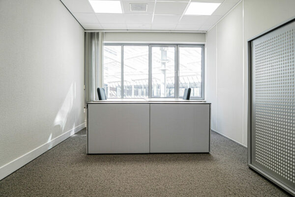 Licht en modern kantoor met twee bureaustoelen aan een groot raam aan de Burgemeester van Karnebeeklaan.